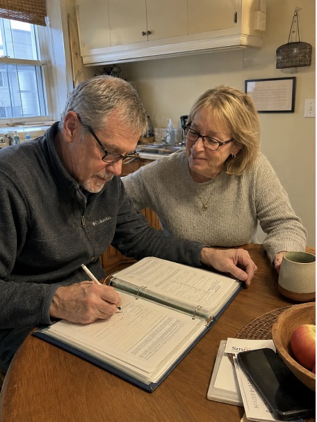 A couple filling in their Family Handover Kit together at the kitchen table.